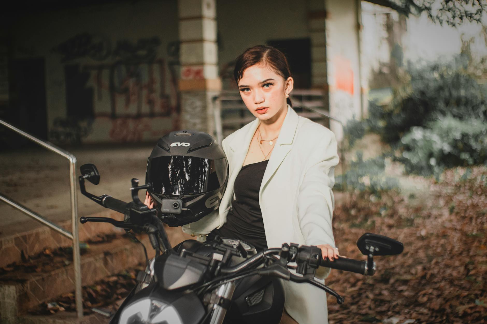 A confident woman wearing a stylish women's motorcycle jacket while standing next to her bike