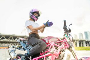 A woman wearing protective womens motorcycle gloves while riding on a scenic highway
