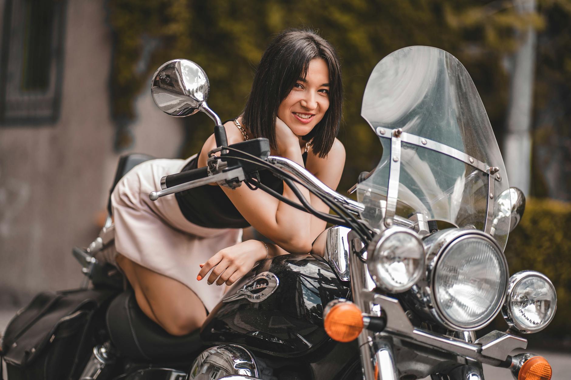 A woman wearing ladies motorcycle gloves confidently rides her motorcycle on a scenic road