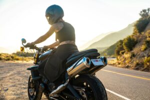 confident woman wearing motorcycle women's gear while riding on scenic highway